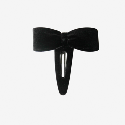 Black velvet bow hair clip on an off white background