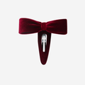 Red velvet bow hair clip on an off white background