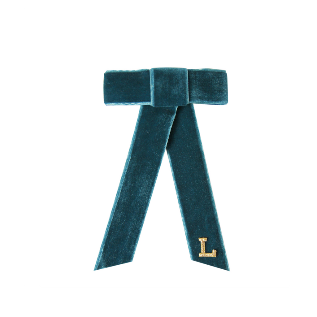 Monogrammed teal velvet hair bow with a gold letter 'L' on a white background