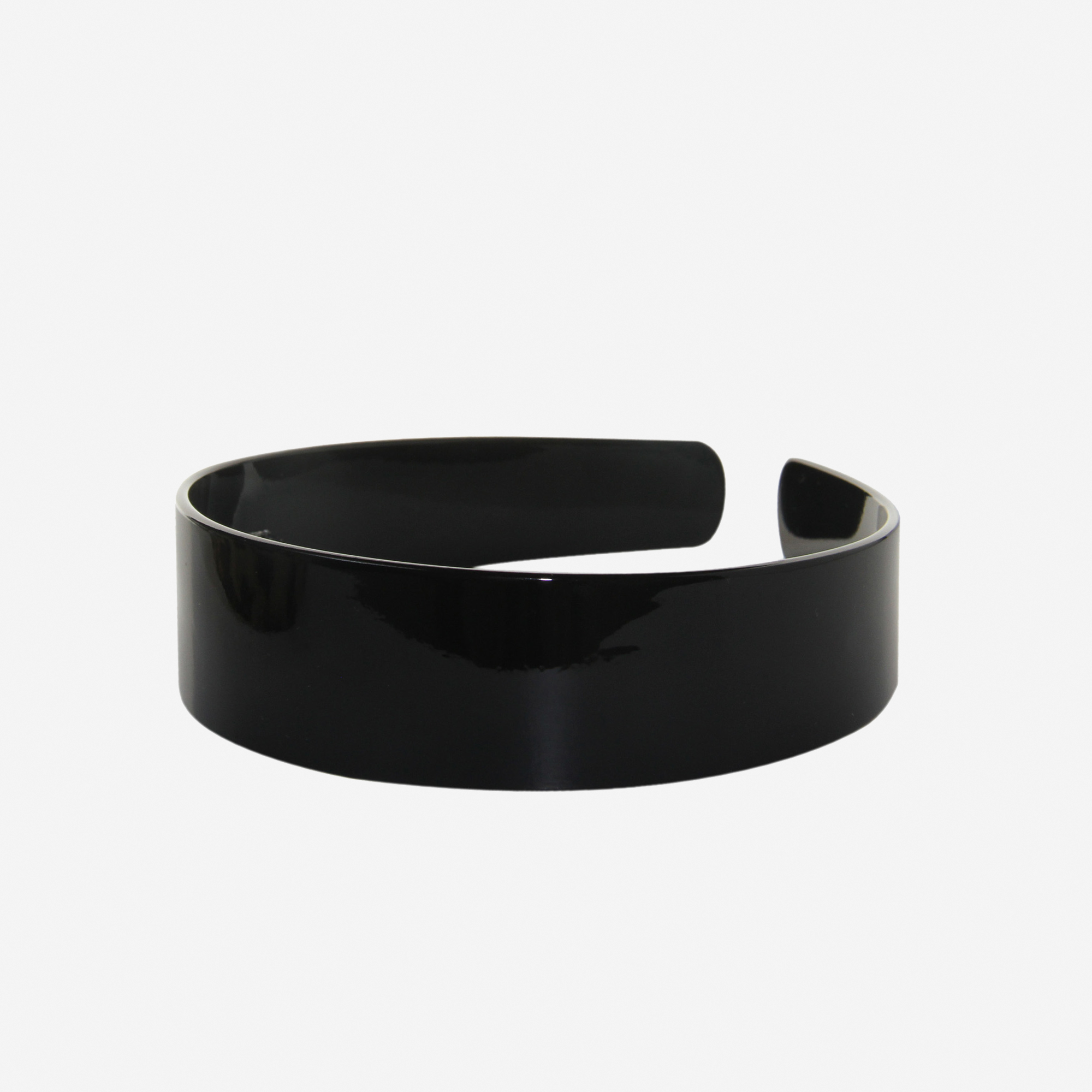 A glossy black resin hairband on a off white background