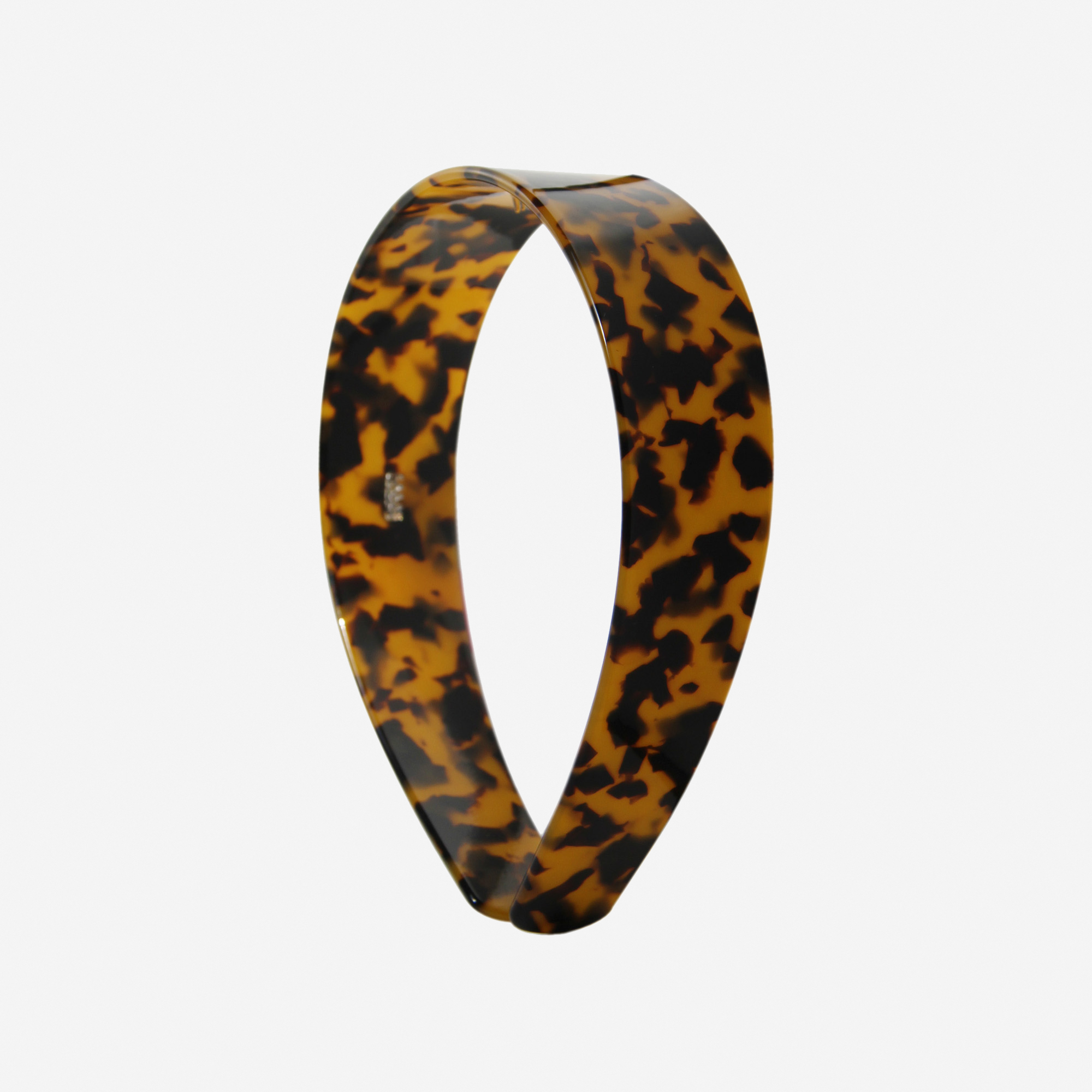 A glossy dark tortoiseshell resin hairband on a off white background
