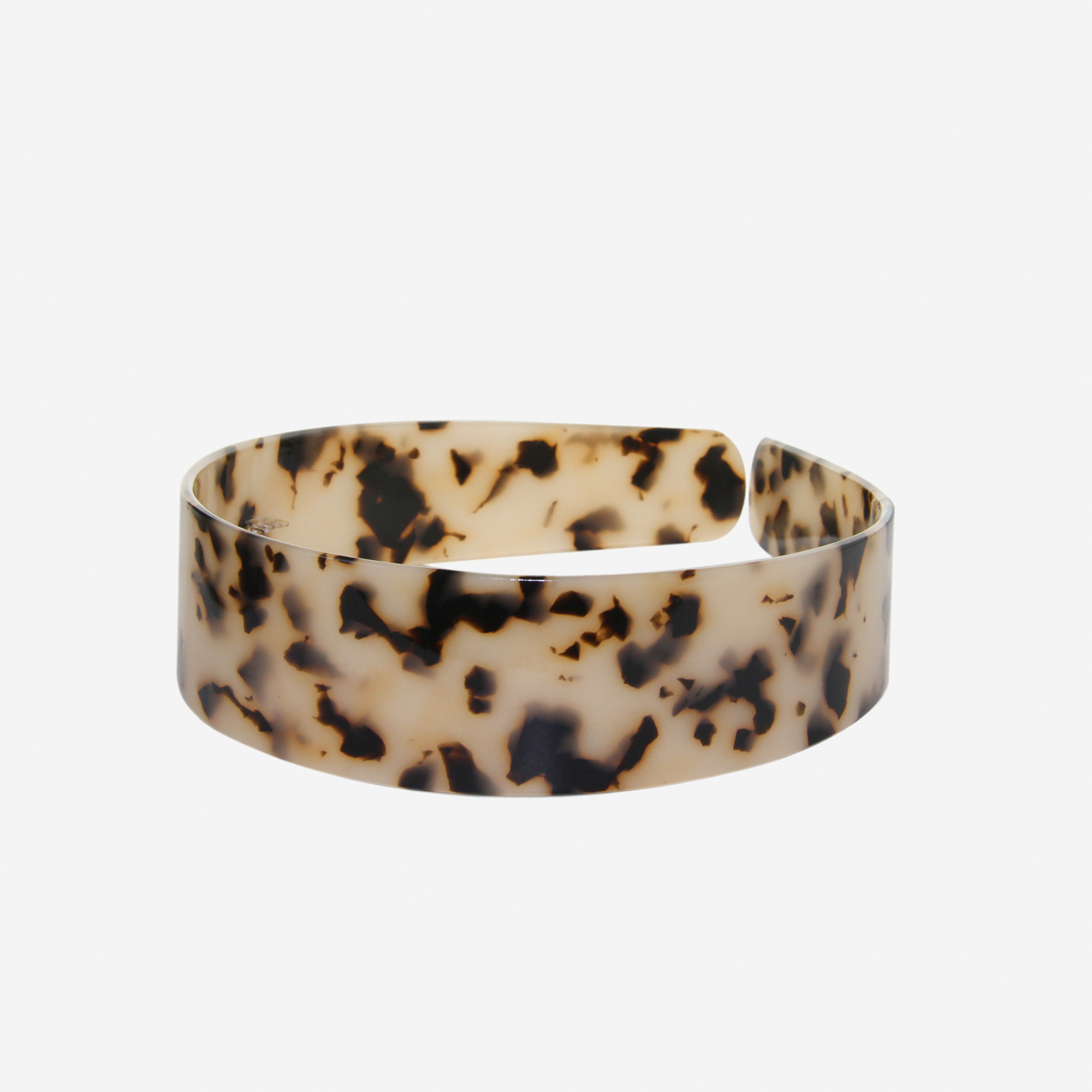 A glossy light tortoiseshell resin hairband on a off white background