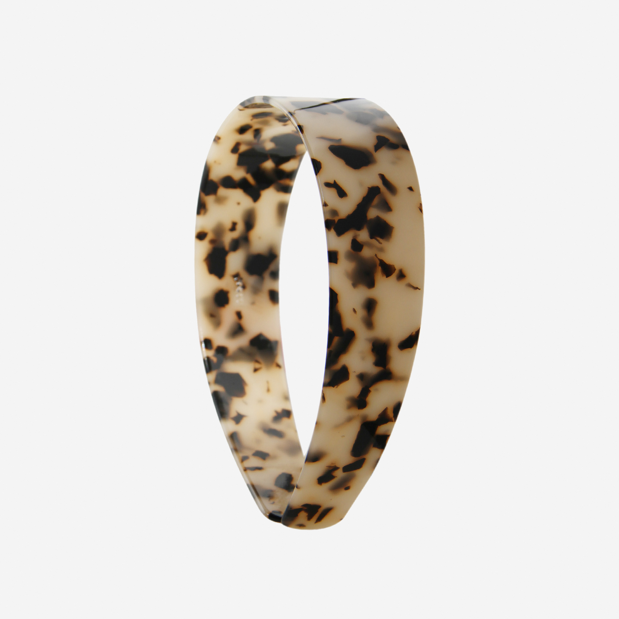 A glossy light tortoiseshell resin hairband on a off white background