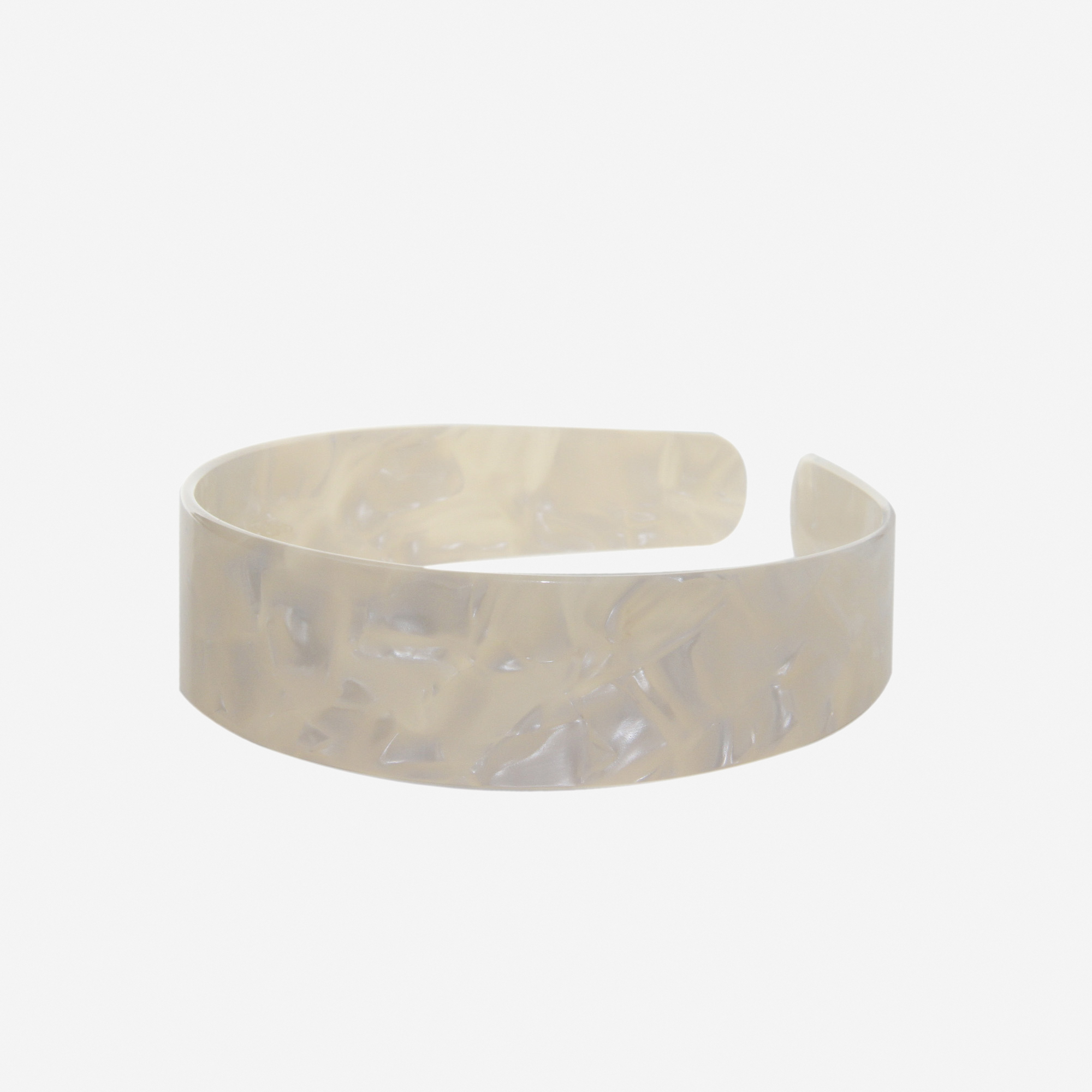 A glossy mother of pearl resin hairband on a off white background