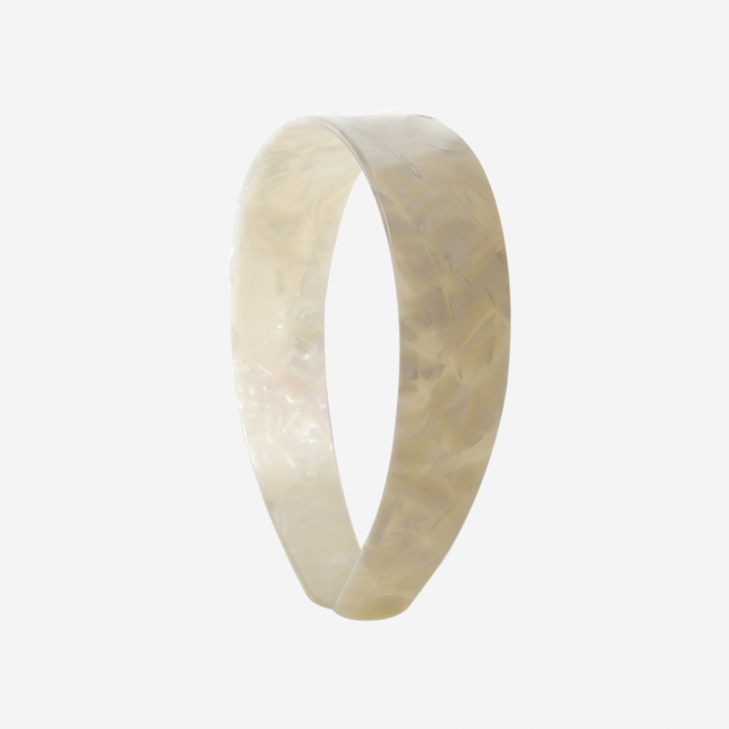 A glossy mother of pearl resin hairband on a off white background