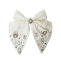 Statement white hair bow with pearl and crystal embellishments on a white background