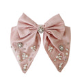 Statement pink hair bow with pearl and crystal embellishments on a white background