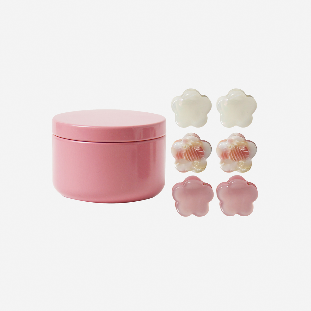 Set of 6  mini flower pink hair claws next to a pink tin they come packaged in